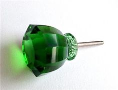 a green glass bead on a white surface with a screwdriver in the foreground