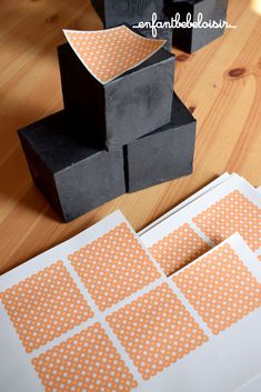 several pieces of black paper with orange polka dots on them sitting on a wooden table