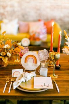 a wooden table topped with plates and candles