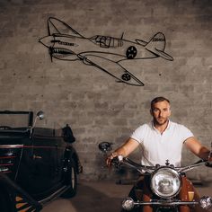 a man sitting on a motorcycle in front of a wall with an airplane drawn on it