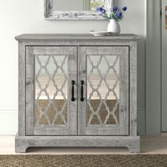 a white wooden cabinet with glass doors in front of a mirror and rug on the floor