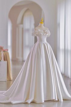 a white wedding dress on display in a room with columns and arches, along with other decorations