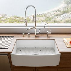 a white sink sitting under a window next to a counter top with a cutting board on it