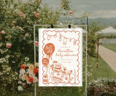 an orange and white sign sitting on top of a lush green field next to flowers