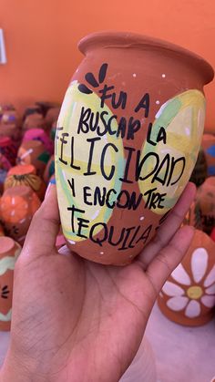 a hand holding a clay pot with writing on it