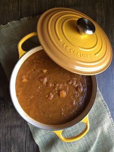 a yellow pot filled with food on top of a wooden table