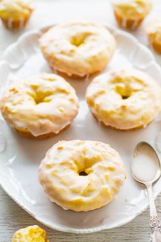 four glazed donuts on a white plate with a spoon