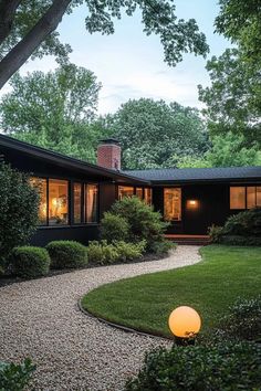 a modern house with large windows and green grass in the front yard, surrounded by trees