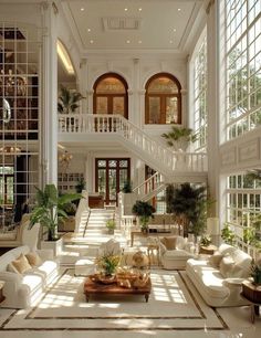 a large living room filled with lots of white furniture and tall windows in the ceiling