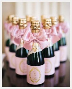 several bottles of champagne with pink bows on them