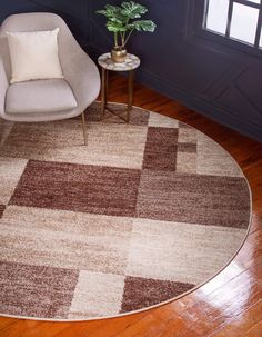 a living room with a chair and rug on the wooden floor next to a potted plant