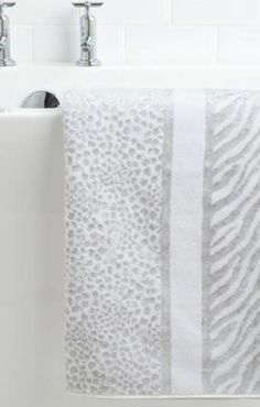 a white towel hanging on the side of a bathroom sink next to two faucets