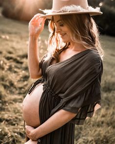 a pregnant woman wearing a hat in a field