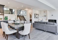 a dining room table with chairs and a couch in front of the stairs leading up to an open floor plan