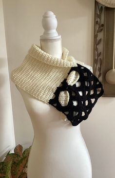 a white mannequin wearing a black and white crochet cowl scarf