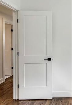 an empty room with a white door and hard wood floors