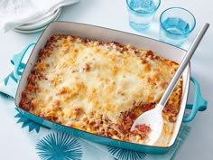 a casserole dish with meat and cheese in it on a blue napkin next to a spoon