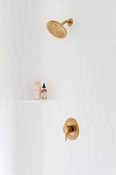 a bathroom with white walls and hexagonal tiles on the wall, including a shower head