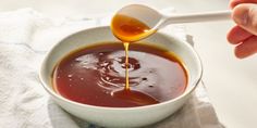 a person pouring sauce into a bowl on top of a white towel with a spoon