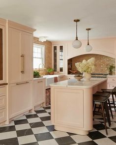 a kitchen with checkered flooring and pink cabinets in the center, along with black and white tiles on the floor