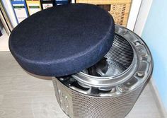 a black cushion sitting on top of a trash can in front of a bookshelf