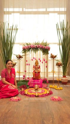 a woman sitting on the floor in front of a flower arrangement with flowers around her