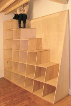 there is a book shelf with books on it and a cat figurine sitting on top