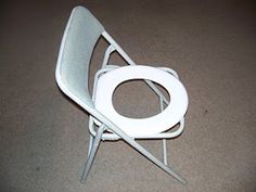 a white chair sitting on top of a floor next to a pair of metal scissors