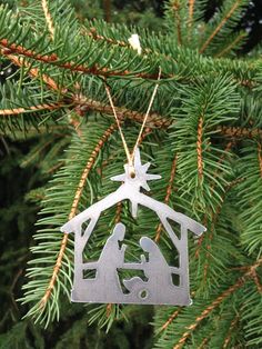 a christmas ornament hanging from a tree with a nativity scene on it