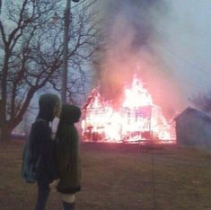 two people standing in front of a fire