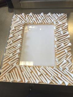 a white square frame made out of wooden sticks on a counter top with a mirror in the middle