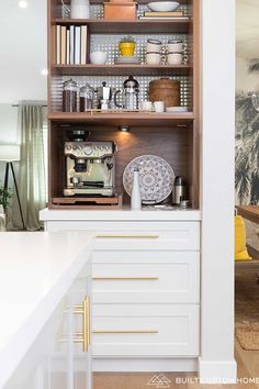 an open cabinet in the middle of a kitchen with plates and bowls on it's shelves