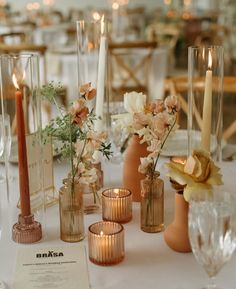 there are many vases and candles on the table