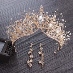 a tiara and earrings are laying on a wooden table next to a pair of scissors