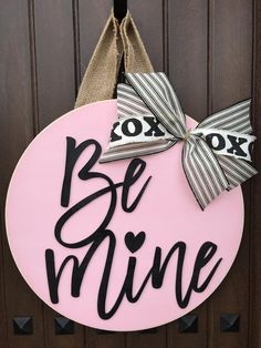 a pink door hanger that says be mine with a bow hanging on the front