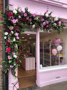 a pink store front with flowers and balloons