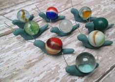 several different colored glass balls on a wooden table with one being blown off by the wind