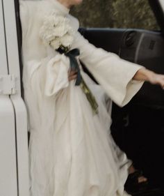 a woman in a wedding dress getting out of a limo