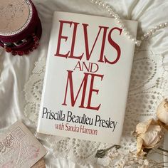 the book elviss and me is laying on a white bed with some other items