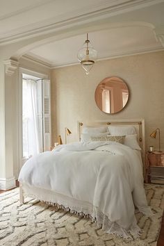 a bedroom with a bed, mirror and rug on the floor in front of it