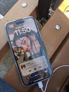 a cell phone sitting on top of a wooden bench next to a charger plugged in