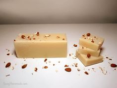 two bars of soap sitting on top of a white counter next to nuts and seeds