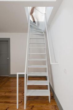 there is a ladder going up to the top floor in this room with wood floors and white walls