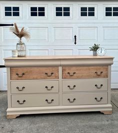 an old dresser has been painted white and is in front of a garage door with a clock on it