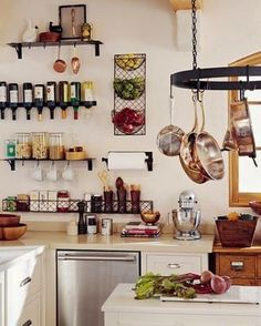 a kitchen with pots and pans hanging on the wall above the sink, next to a dishwasher