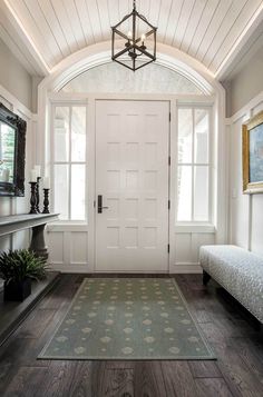 a room with a bed and a rug in front of a white door that has two windows