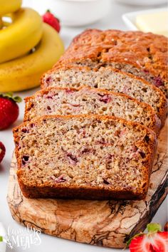 slices of banana bread on a cutting board with strawberries and bananas in the background