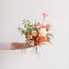 a person holding a bouquet of flowers in their hand with white gloves on the arm