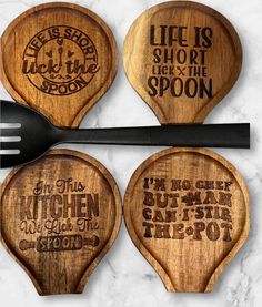 four wooden spoons with words on them and one has a fork in the middle