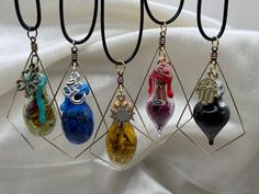 four necklaces with different colored glass items hanging from it's sides on a black cord